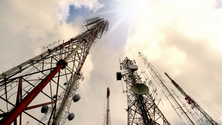 Group of antenna towers against cloudy sky.