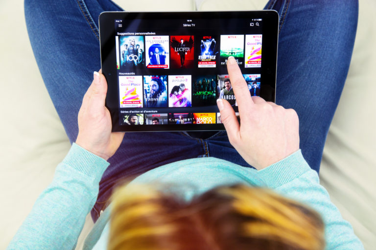 A woman watches Netflix on her tablet.