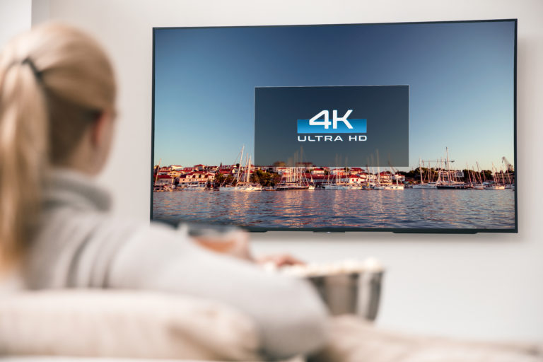 A woman watches 4K ultra-high definition television on her sofa.
