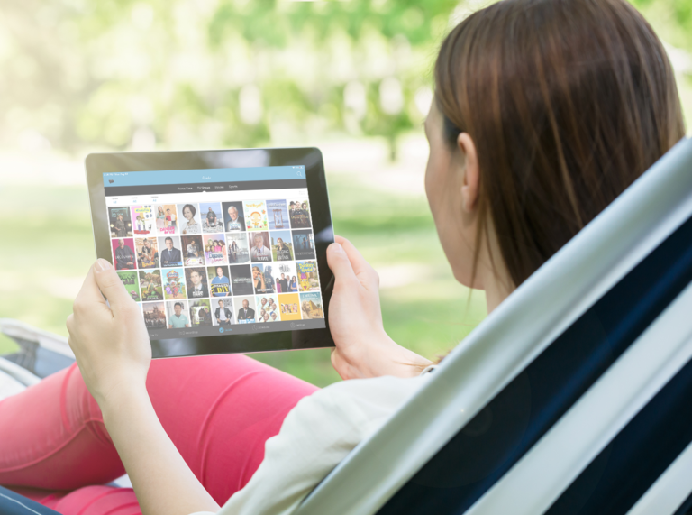 Woman sits in hammock outdoors holding tablet