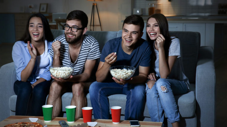 Friends watching TV in evening at home