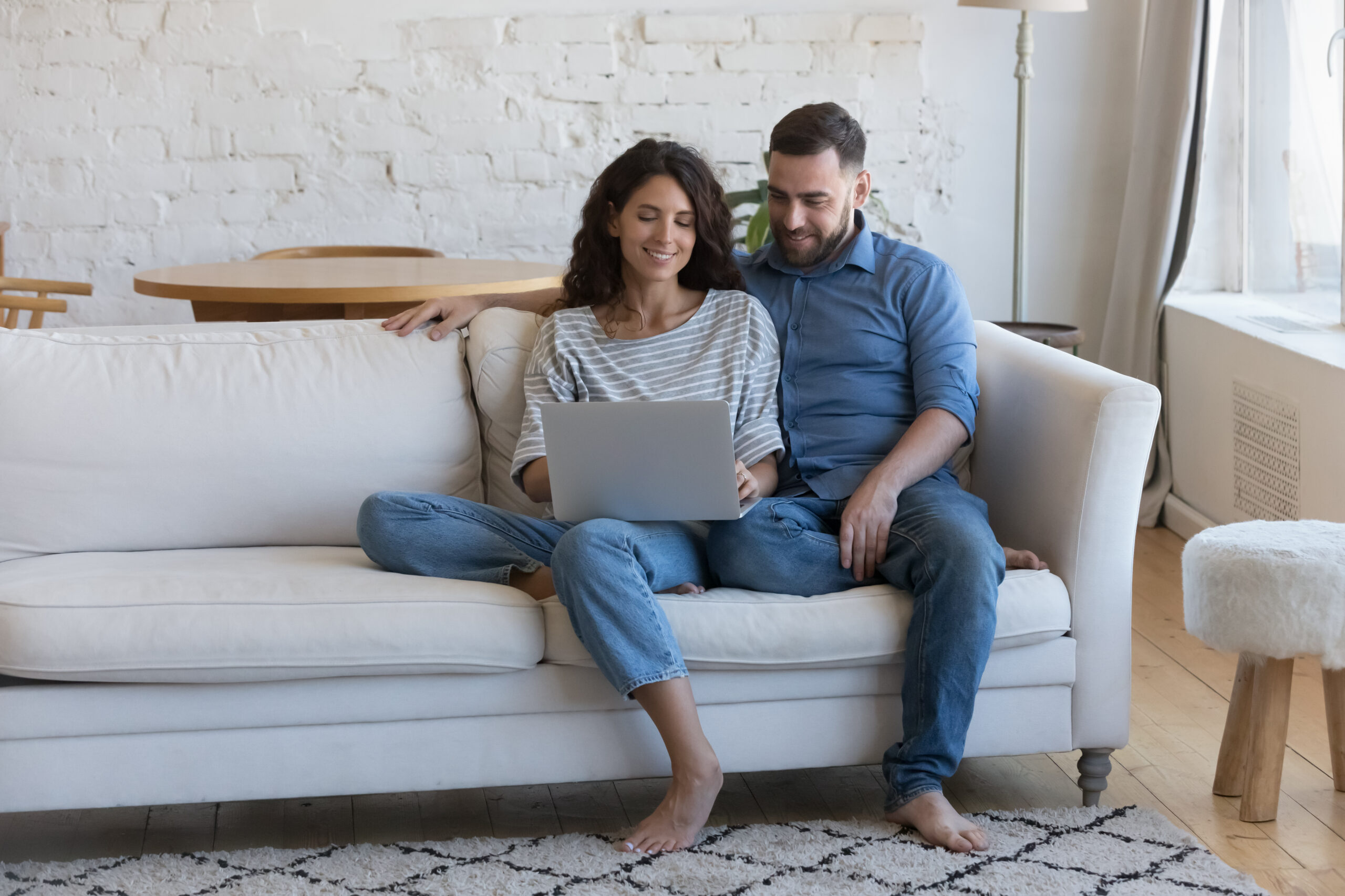 millennial couple in love sitting on couch at home